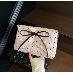 Detailansicht der rosa gesteppten Handtasche mit schwarzer Schleife und Kettenriemen