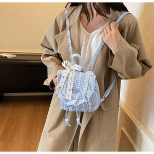 Close-up of blue plaid mini backpack featuring white lace bows and ruffled edge detail