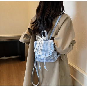 Blue and white plaid mini backpack with lace bow decoration shown on a model's back