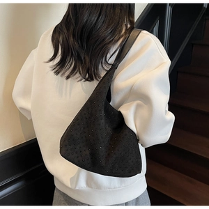 Détail d'un sac hobo noir orné de strass portés sur un sweat à capuche blanc