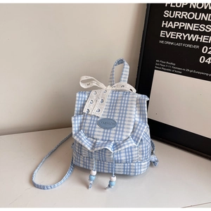 Detail of blue plaid mini backpack featuring lace bow and decorative ruffle edges