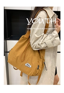 Detalle de mochila de nailon amarillo en modelo con parche nube y cordón lateral