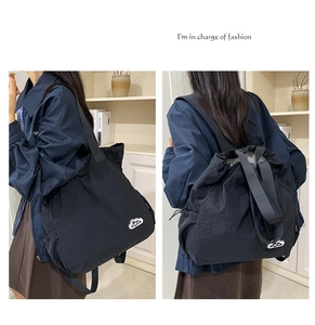 Detalle de la mochila grande de nailon negro con cordón y parche decorativo de nube