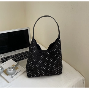 Détail du cabas noir en strass avec texture daim sur un bureau blanc