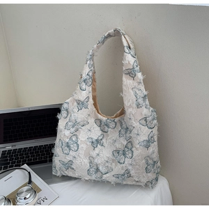 Detail of lace tote bag with textured butterfly embroidery and raw fringe edges