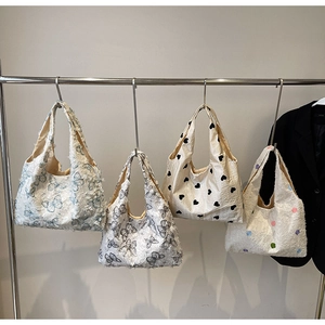 Detail of four textured canvas tote bags with heart and butterfly prints on a rack