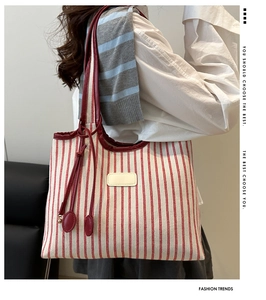 Macro view of red striped canvas tote with leather straps and decorative hanging charms
