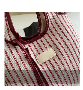 Detailed macro view of red striped canvas fabric texture and red leather trim on tote bag