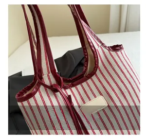 Close-up of red and white striped canvas tote bag with faux leather handles and patch