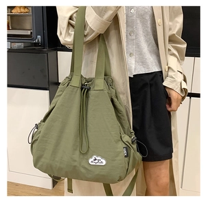 Detalle del bolso tote de nailon verde militar con parche de nube y correa en modelo