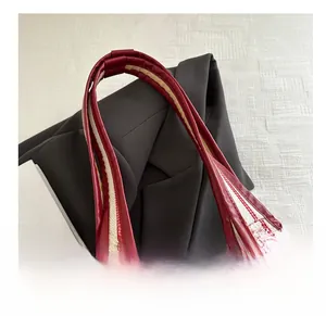 Detail of red leather handles and striped canvas on a large tote bag for women