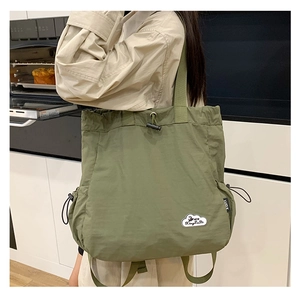 Detalle del bolso tote de nailon impermeable verde hierba con cierre de cordón y logotipo