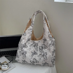 Chic off-white tote bag with butterfly print and 3D fringe detail in lifestyle setting