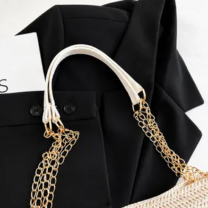 Detail eines weißen Lederriemens mit dreifacher Goldkette an einer gewebten Tragetasche