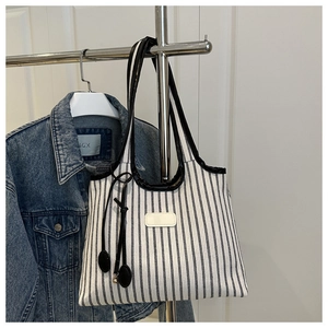 Close-up of black and white striped canvas tote bag with leather handles on a display rack