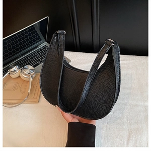 Detailed view of black lychee grain texture on a stylish crescent-shaped crossbody bag