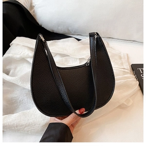 Detail of black pebbled leather crescent bag with zipper closure and solid handle