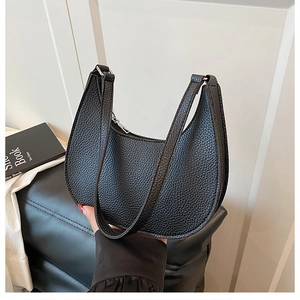 Detail of black lychee texture leather crescent bag with silver zipper and double straps