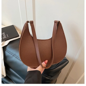 Detailed close-up of brown litchi pattern leather grain on half-moon shaped handbag