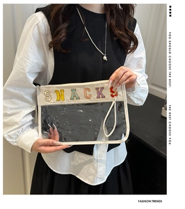Detail of transparent PVC handbag with colorful SNACKS letter embroidery and white leather trim