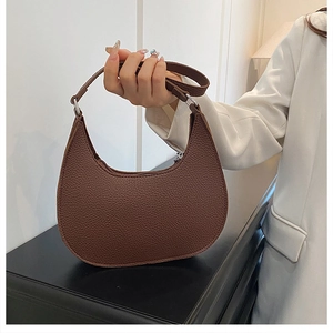 Detail of dark brown lychee leather hobo bag with zipper and metal buckle accents