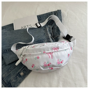 Detalle de riñonera de nailon blanca con flores rosas sobre ropa vaquera azul