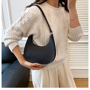 Close-up of black lychee grain leather hobo bag worn by model in a stylish setting