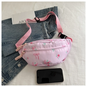Detail van roze bloemen schoudertas met rozenprint en geweven riem op witte textuur