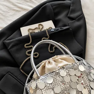 Detail of silver sequin bucket bag with beige satin drawstring closure and strap