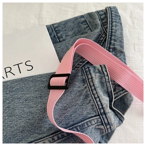 Detail van blauwe denimstof met roze geweven band en zwarte plastic verstelgesp