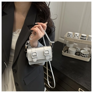 Detalle de mini bolso plateado con asa de cadena acrílica y hebillas decorativas