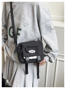 Detail of black nylon crossbody bag featuring dual buckle closure and adjustable strap