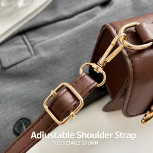 Close-up of adjustable shoulder strap and polished gold hardware on brown leather bag