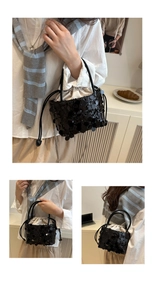 Detail of black sequined bucket bag featuring silk drawstring closure and metal chain strap