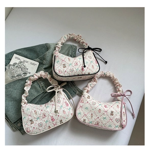 Detailed close-up of pleated white shoulder bags with floral bear prints and ribbon bows