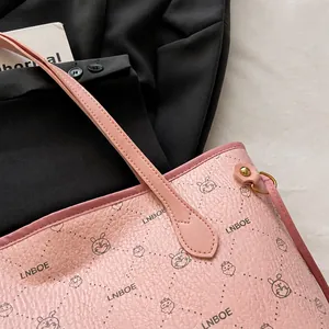 Detailed close-up of pink litchi grain leather tote bag with cute rabbit pattern and stitching