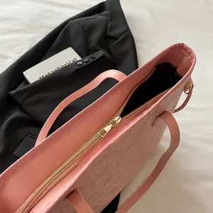 Close-up of pink leather tote bag featuring a smooth gold zipper and LNBOE print