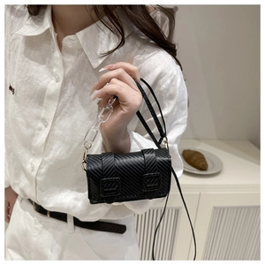 Dettaglio mini borsa a tracolla nera con texture in fibra di carbonio e catena acrilica
