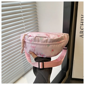 Detail van roze nylon tas met rozenprint, strikmotieven en geweven rits hanger detail