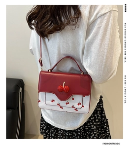 Detalle de bolso bandolera rojo y blanco con estampado de cerezas y adorno 3D