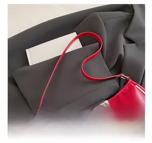 Detail view of red glossy leather handbag with number 96 patch on a grey blazer suit
