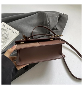 Detail of a brown leather crossbody bag with a leopard scarf and textured flap finish