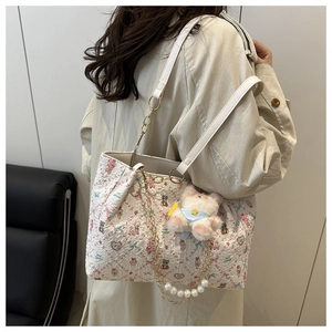 Detail van bloemen tote bag met parelketting en schattige pluche beer aan de tas