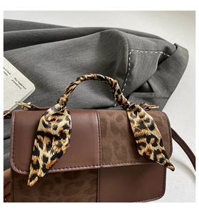 Close-up of brown patchwork handbag with leopard print scarf and smooth leather detail