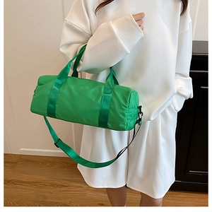 Detail of bright green nylon barrel bag with adjustable strap shown on shoulder