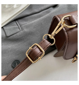 Detail showing high-quality gold hardware and stitching on a dark brown leather handbag