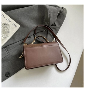Detail of a brown leather rectangular handbag featuring a leopard print scarf handle wrap