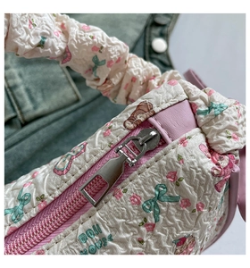 Detailed view of pink floral quilted puffy fabric and metallic zipper on the shoulder bag