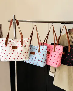 Nahaufnahme modischer Tragetaschen mit Kirschdruck in Weiß, Blau, Rosa und Schwarz