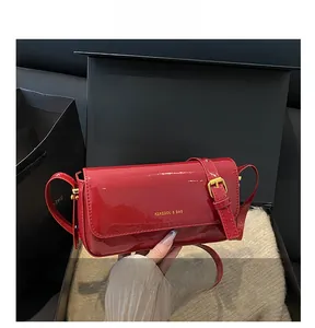 Detail view of glossy red patent leather finish and gold buckle on a retro square bag